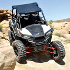 Polaris RZR driving on rocks out in the desert, equipped with AMS M4 Evil all terrain 8-ply radial UTV tires, designed with rugged construction to protect against punctures and obstacles.
