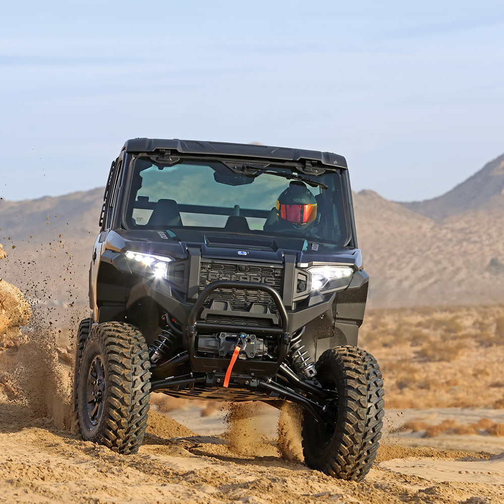 Kenda Cross Trail UTV directional 8-ply Radial tire mounted on Polaris, driving in sand dunes and turning sharply, displaying high traction directional tread design.