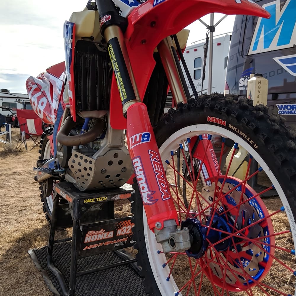 An up close image of the Kenda Millville II front MX tire mounted on a 4-stroke dirt bike.