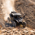 UTV driving downhill on rocky and desert terrain with dust coming up in the background. EFX MotoVator R/T tires installed.