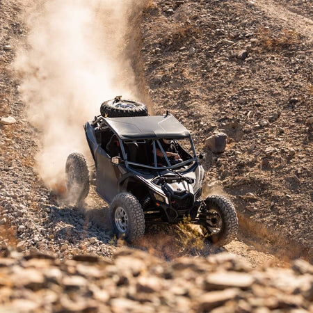 UTV driving downhill on rocky and desert terrain with dust coming up in the background. EFX MotoVator R/T tires installed.