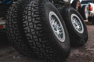 Close-up of three Valor Tango Tires mounted on silver wheels on a dirt surface.