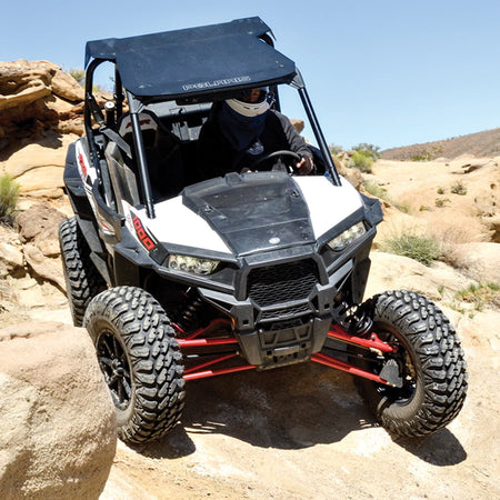 Polaris RZR driving on rocks out in the desert, equipped with AMS M4 Evil all terrain 8-ply radial UTV tires, designed with rugged construction to protect against punctures and obstacles.