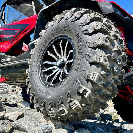 A set of 32x10.00R14 Roctane T4 UTV all-terrain tires mounted on a red Honda Talon, parked on some rocks outside in the desert.