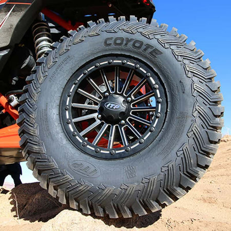 ITP Coyote radial tire installed on SXS, parked on rocks in desert.