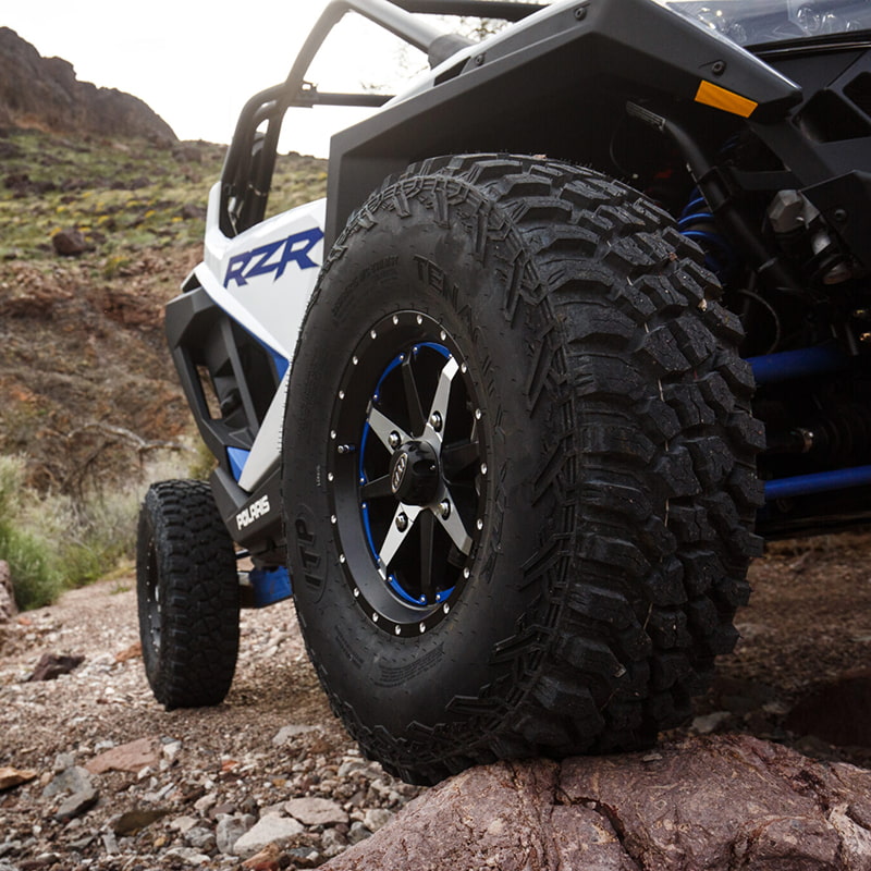 ITP Tenacity tires mounted on ITP rims and installed on a RZR climbing rocky terrain in the mountains.