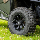 A Sedona Coyote 28x10R14 UTV 8-Ply Radial tire mounted on a black 14x7 Sedona UTV wheel, installed on a Polaris SXS parked in the grass.