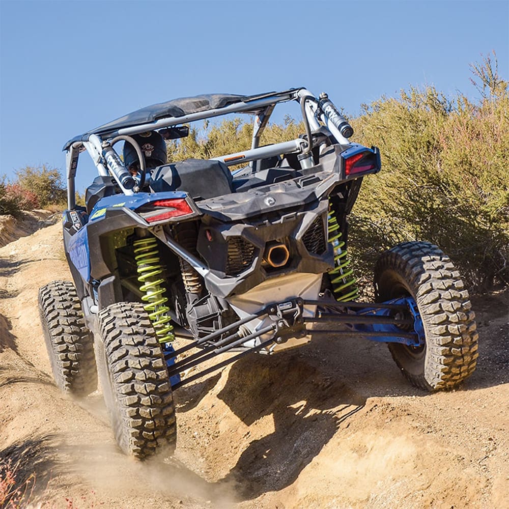 Sedona Rockabilly tires mounted and installed on a Can Am Maverick X3 driving on a deeply rutted trail in the desert, easily maneuvering through rugged trails thanks to the high traction ultra-tough tires from Sedona.