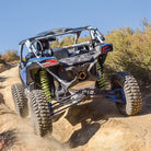 Sedona Rockabilly tires mounted and installed on a Can Am Maverick X3 driving on a deeply rutted trail in the desert, easily maneuvering through rugged trails thanks to the high traction ultra-tough tires from Sedona.