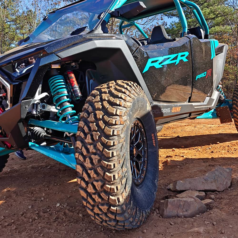SunF Trail Titan A066 tire mounted on a Polaris RZR Pro R parked on a mountain trail, showcasing the tire's 10-ply rugged durability and traction for all-terrain trail riding and competition courses.