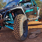 SunF Trail Titan A066 tire mounted on a Polaris RZR Pro R parked on a mountain trail, showcasing the tire's 10-ply rugged durability and traction for all-terrain trail riding and competition courses.