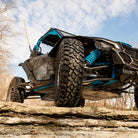 A close up view of the SuperATV Incursion AT tire mounted on a UTV, parked on a rocky ledge.