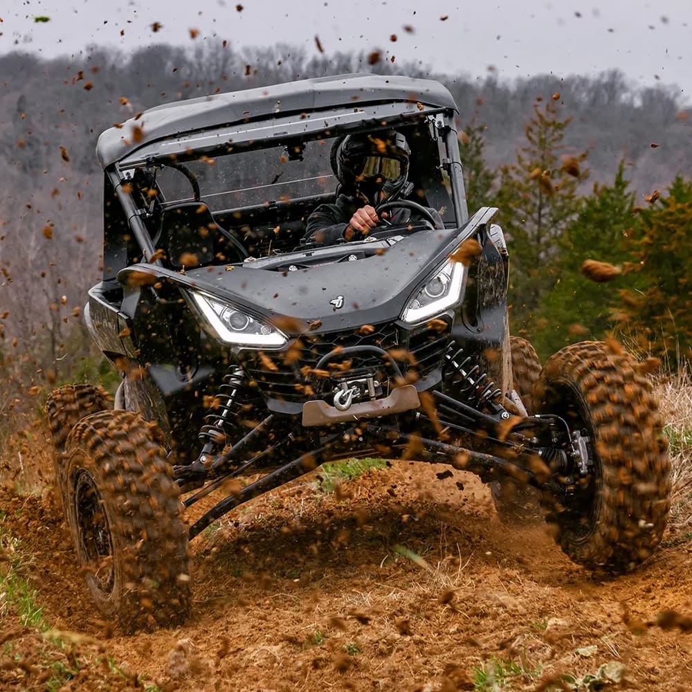 A new Segway Side-by-Side ripping through a dirt track, throwing dirt into the air from the super high traction 8-ply bias SuperATV XTWarrior all-terrain and rock tires.