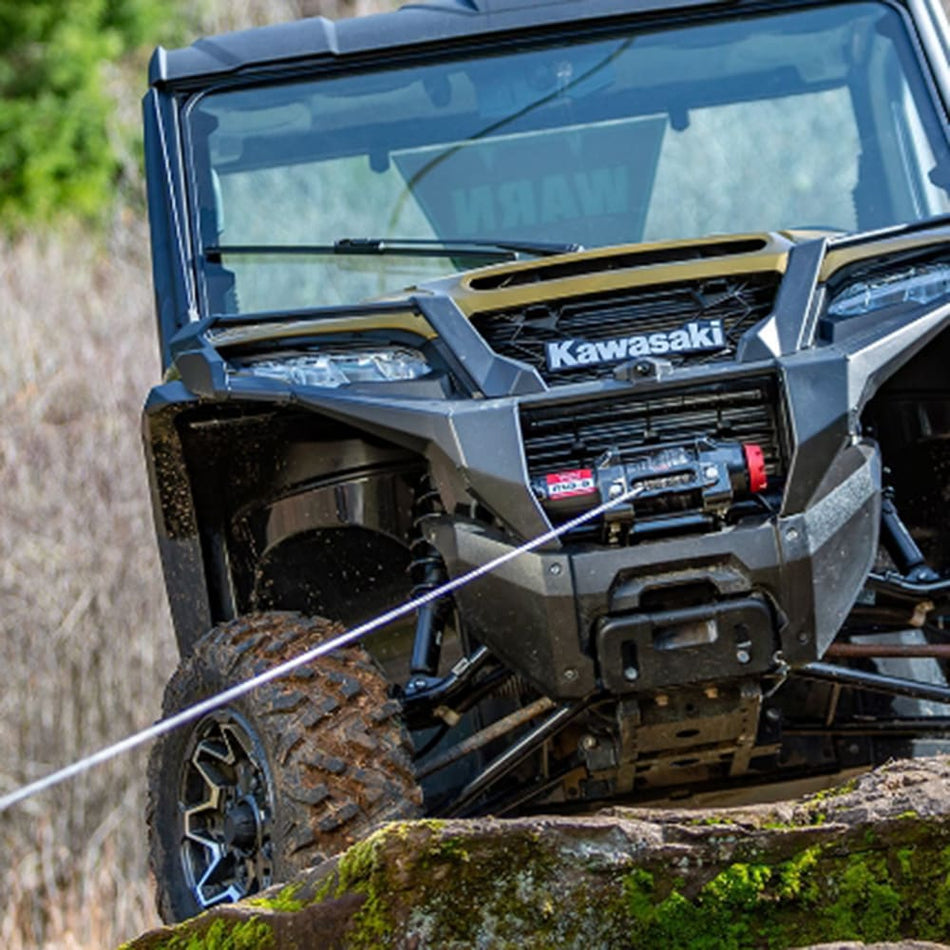 All new Warn R-Series winch installed on Kawasaki UTV, in use pulling the SXS over a log in the woods.